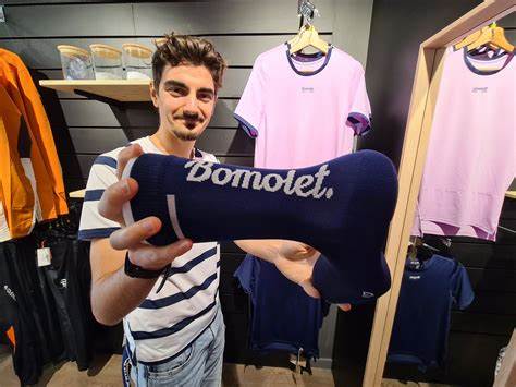 au premier plan un homme tenant une chaussette bomolet, au second plan des articles de t-shirt 